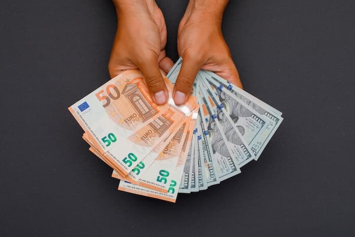 Hands holding fans of euro and US dollar banknotes
